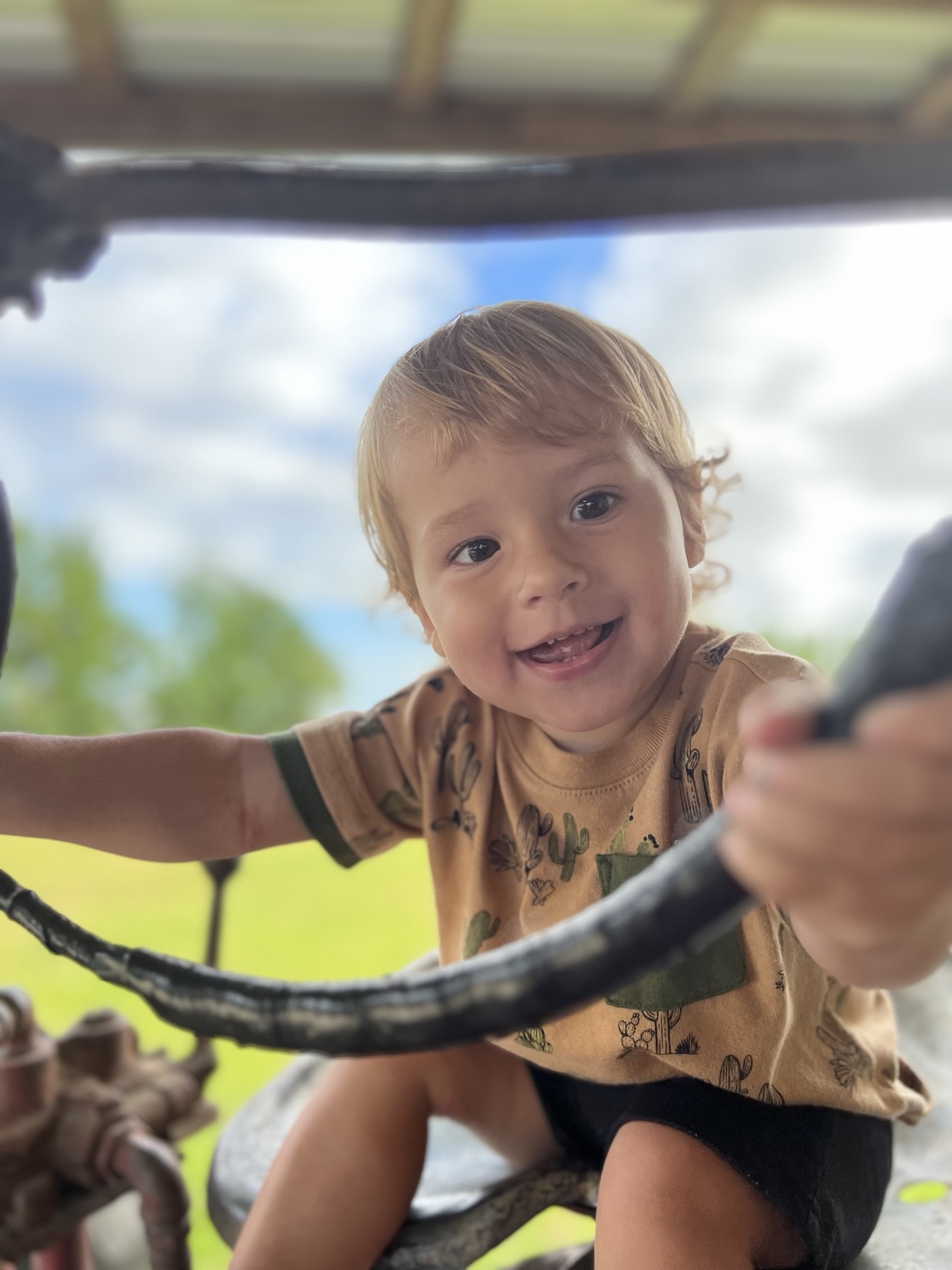 Charlie smiling in a tan shirt while holding a steering wheel
